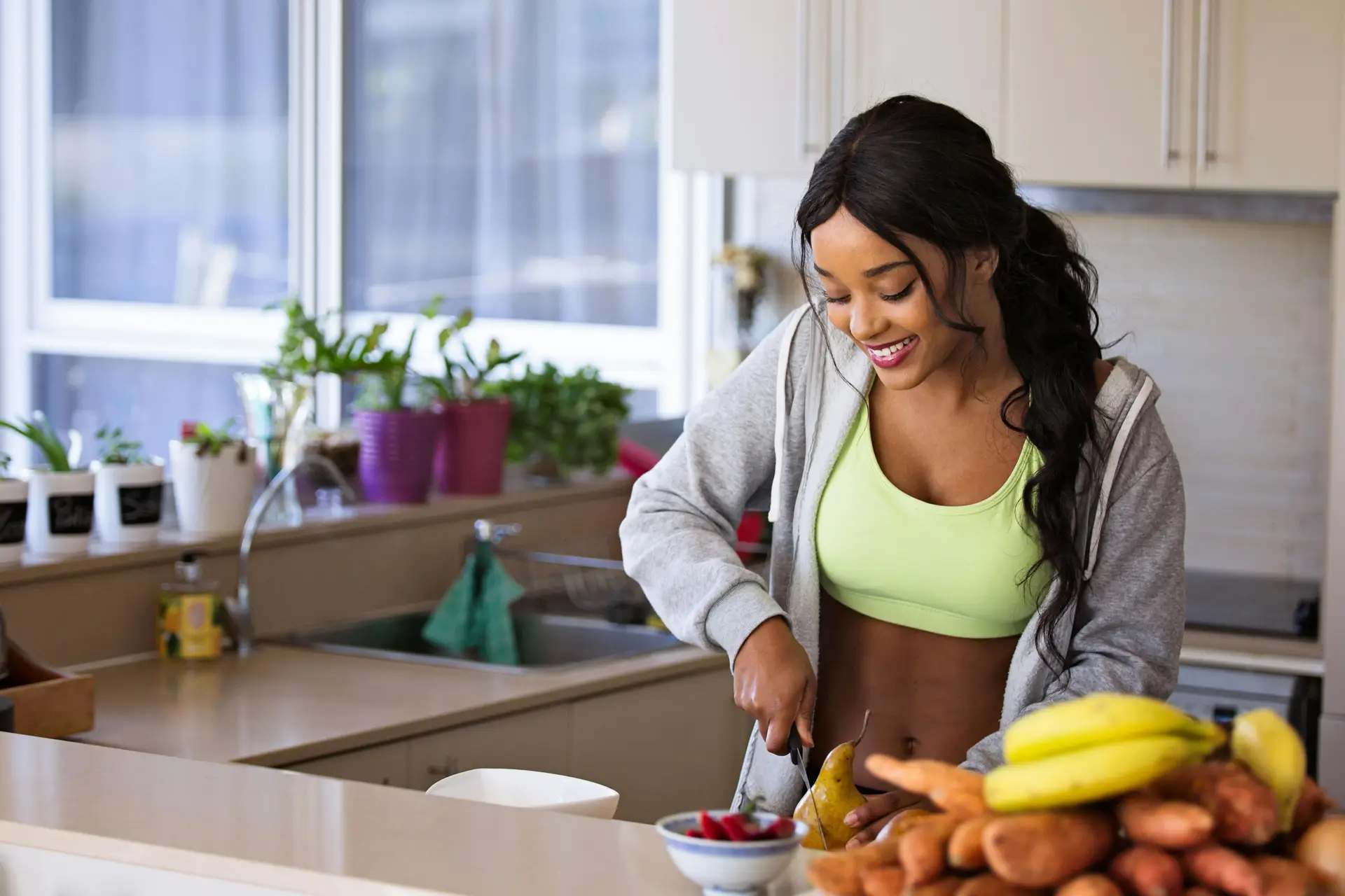 Woman cutting fresh fruits and vegetables as part of a fertility-boosting diet.