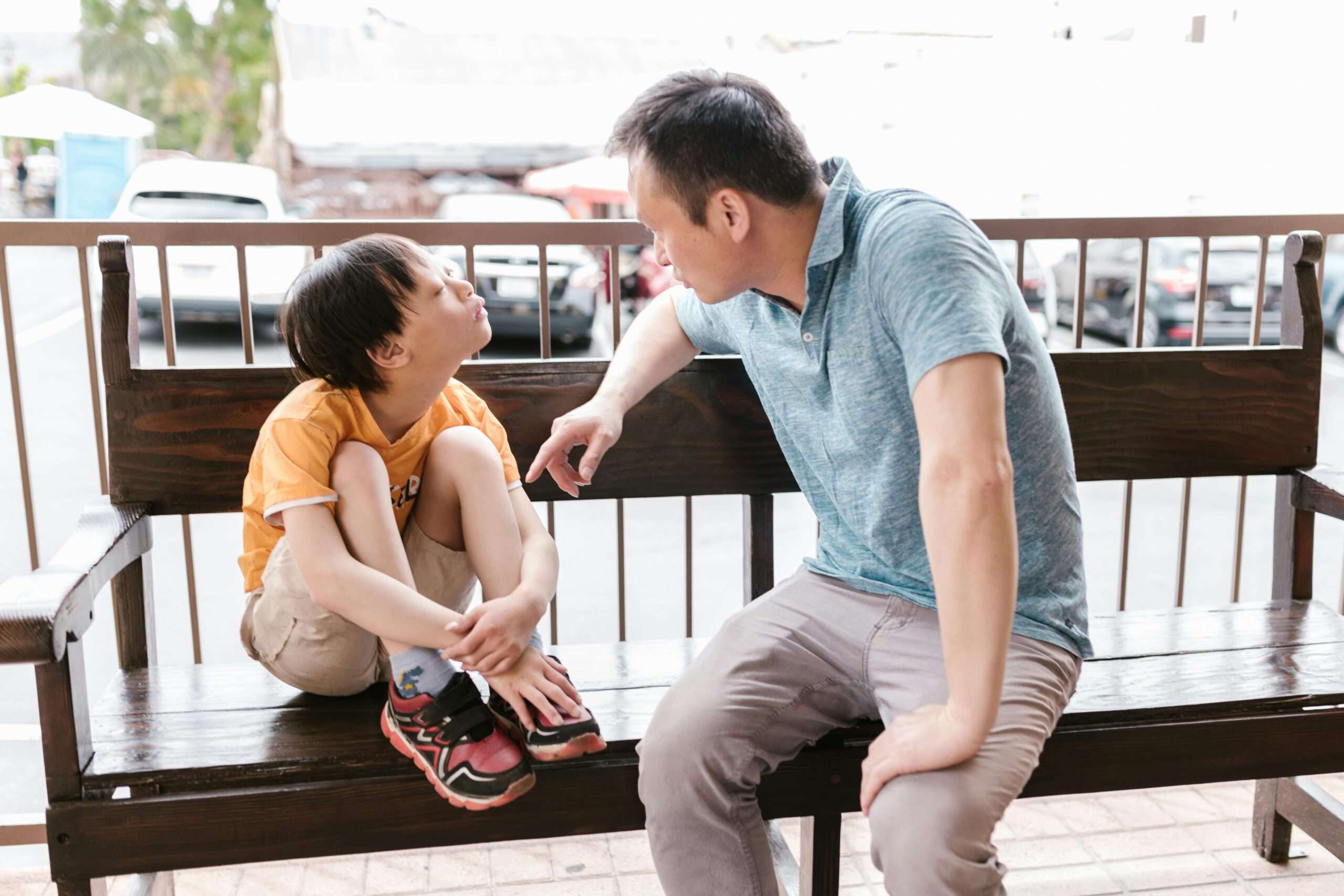 A father sitting on a wooden bench, engaging in a heartfelt conversation with his autistic child, highlighting the Autism Diet Impact on behavior and emotional well-being.